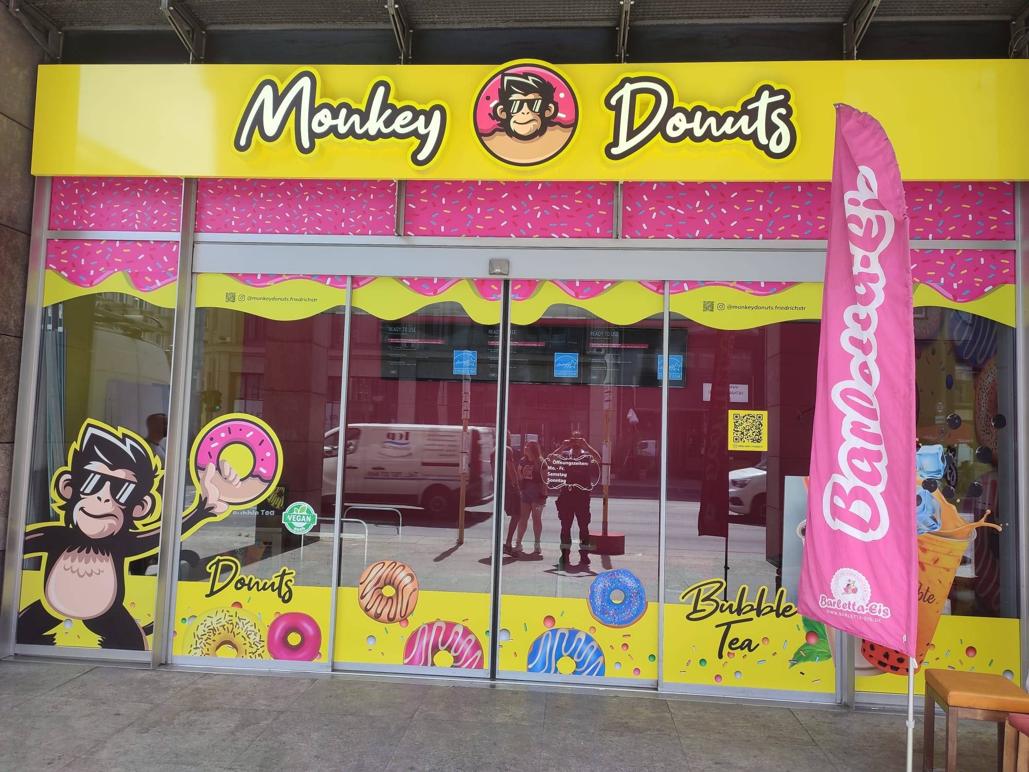 Ladenfront von Monkey Donuts mit Leuchtschrift, Schaufensterfolierung und Beachflag