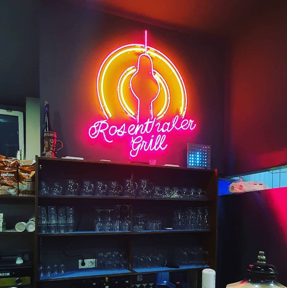 Neon-Schriftzug „Rosenthaler Grill“ mit Fernsehturm-Motiv in Pink und Gelb über einer Bar